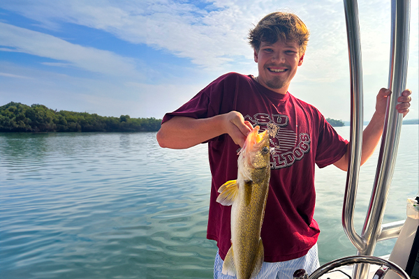 Man holds up a catch during a mountain lake fishing expedition.