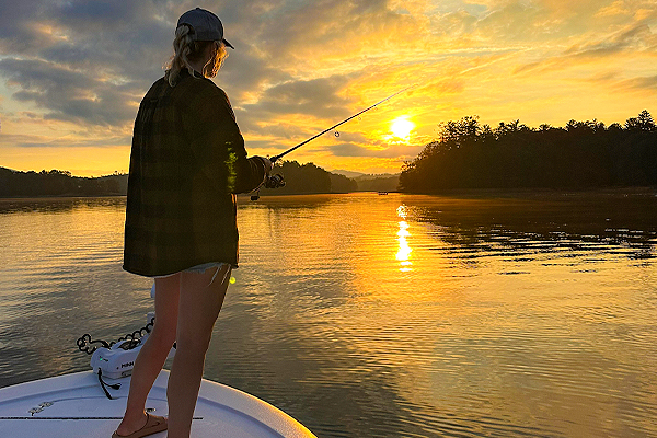 Woman fishing on a lake at sunset.