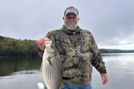  Man poses with fish caught on lake.