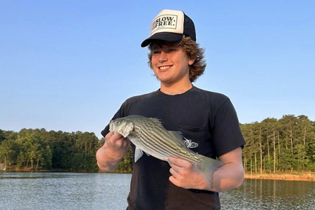  Young adult shows fish caught after lake fishing trip