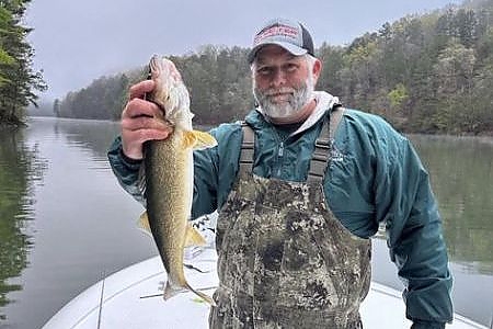  Older man holds up fish caught on lake