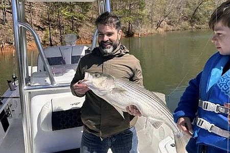  Man and child hold up fish caught on lake.