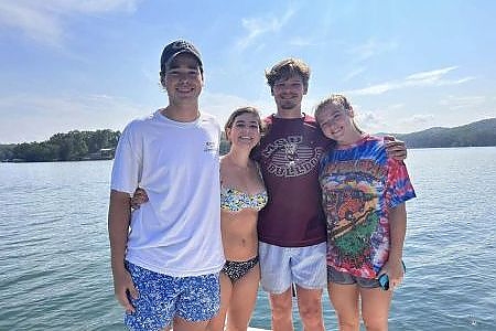  Young adults pose for camera on lake.