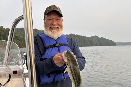  Father poses alone with fish caught on lake.