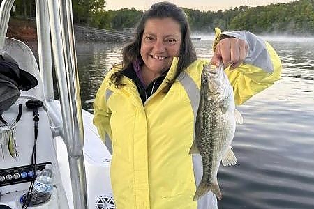  Woman in yellow jacket holds up fish caught on 4-hour trip.