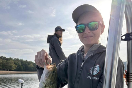  Woman shows off fish caught with sun behind her.