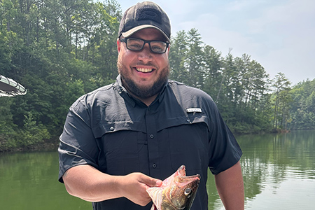 Son poses alone with fish caught on lake.